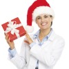 Top Ten Integrative Medical Stories for 2014 Happy doctor woman in santa hat showing christmas present box