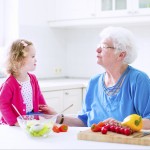 Grandmother and little girl making salad